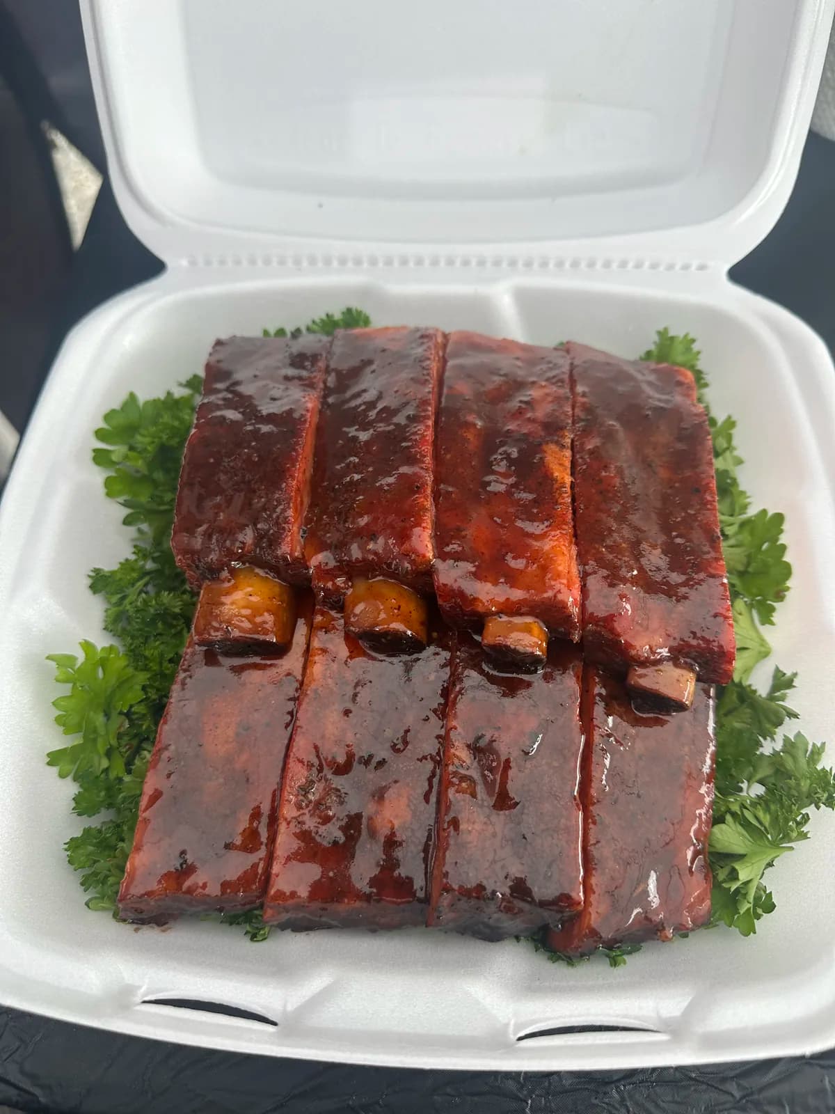 Glossy glazed pork ribs presented on parsley in a competition turn-in box
