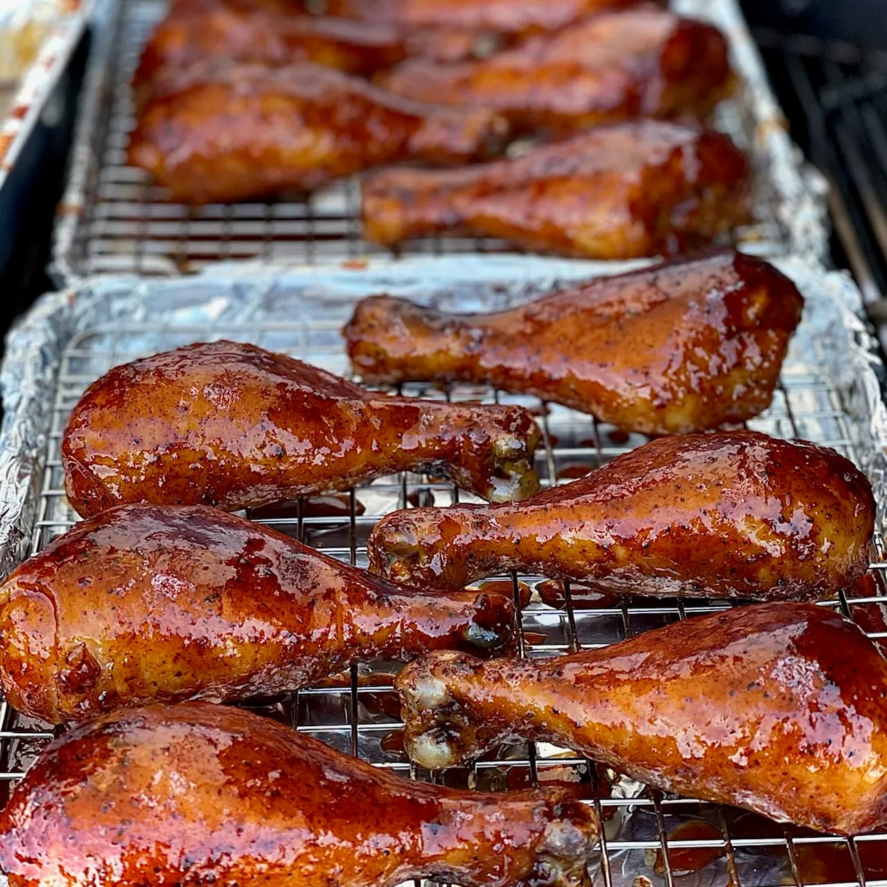Glazed smoked chicken drumsticks resting on wire racks fresh off the smoker